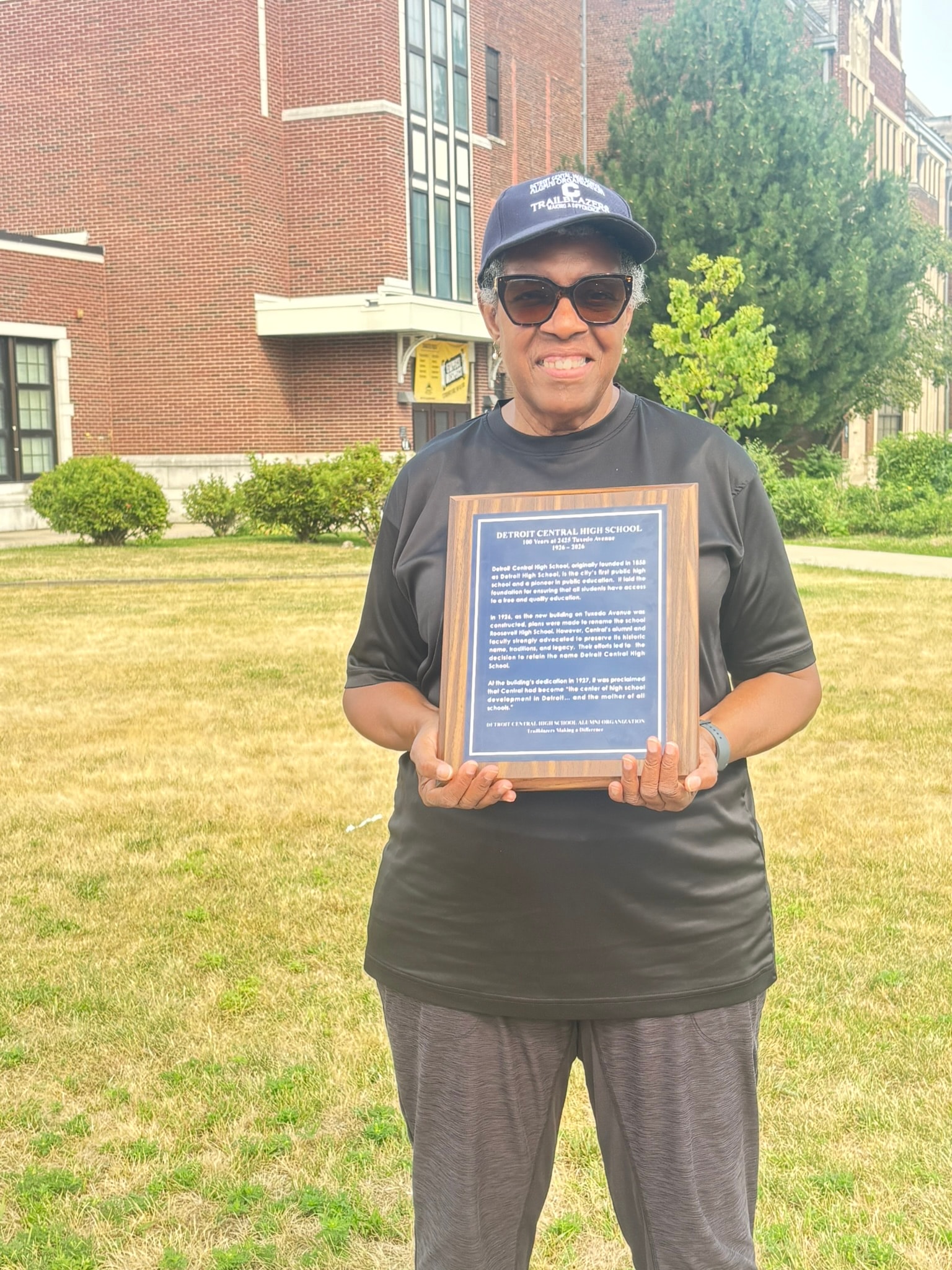 Person holding historical plaque school building