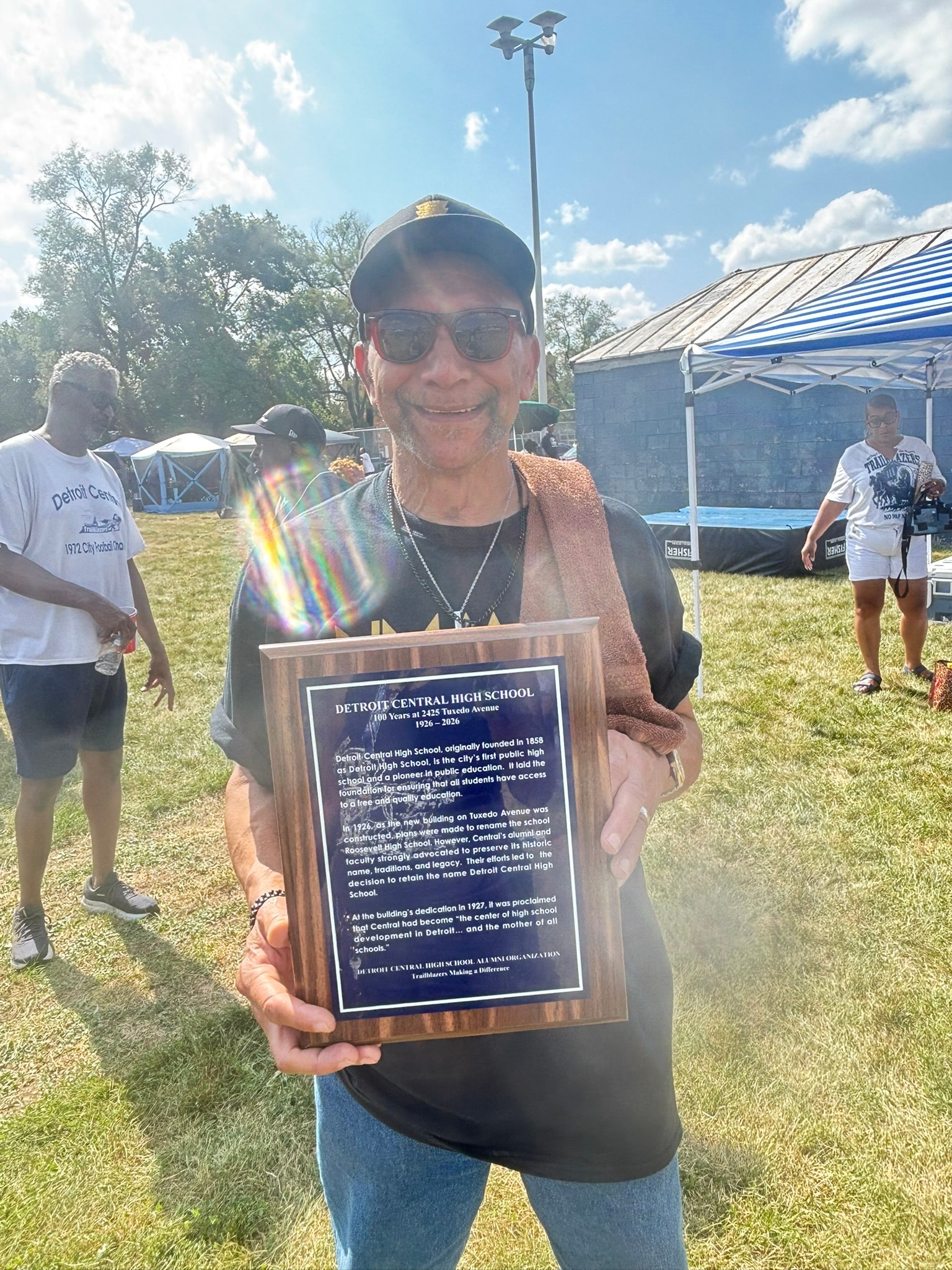 Man holding Detroit Central High School plaque outdoors