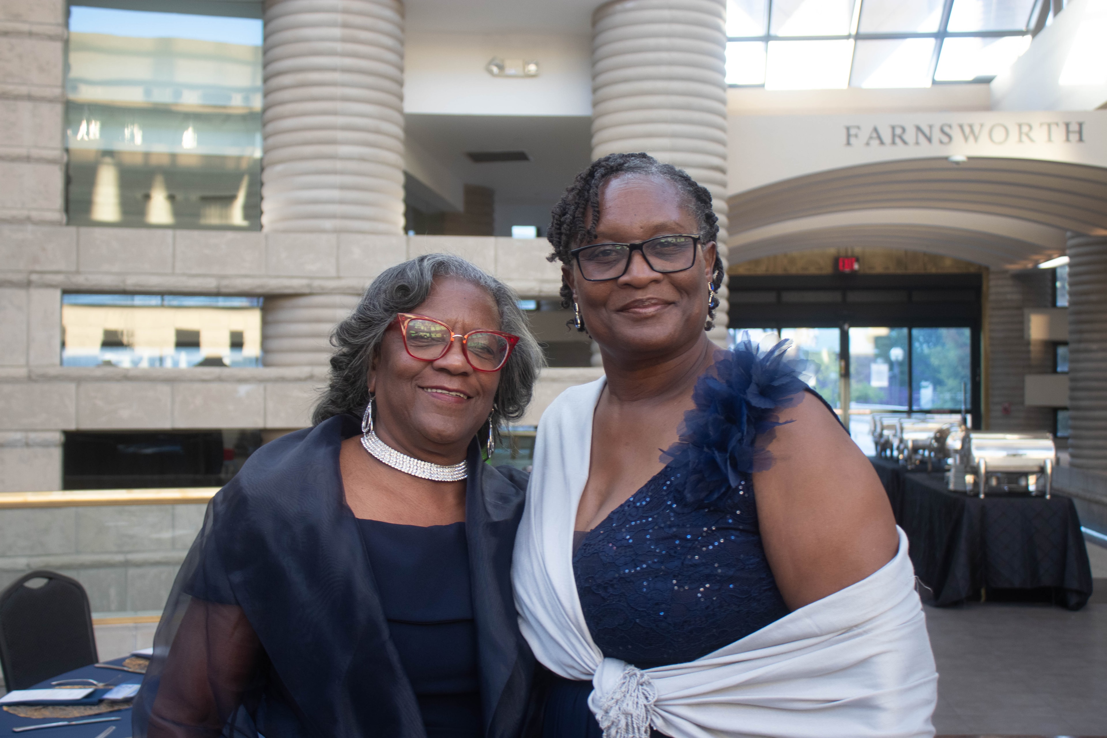Two women posing inside modern building lobby