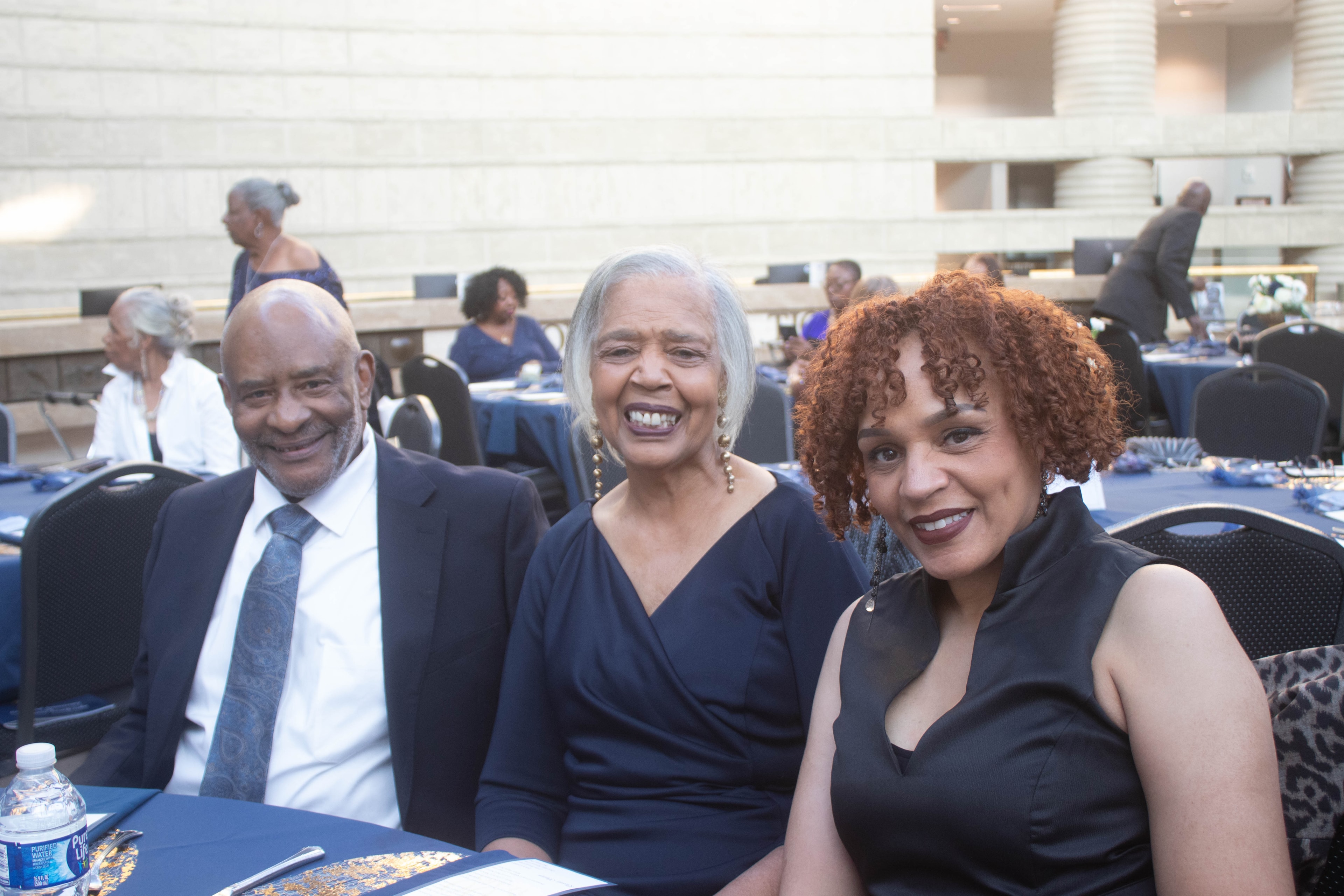 Three people smiling at formal event