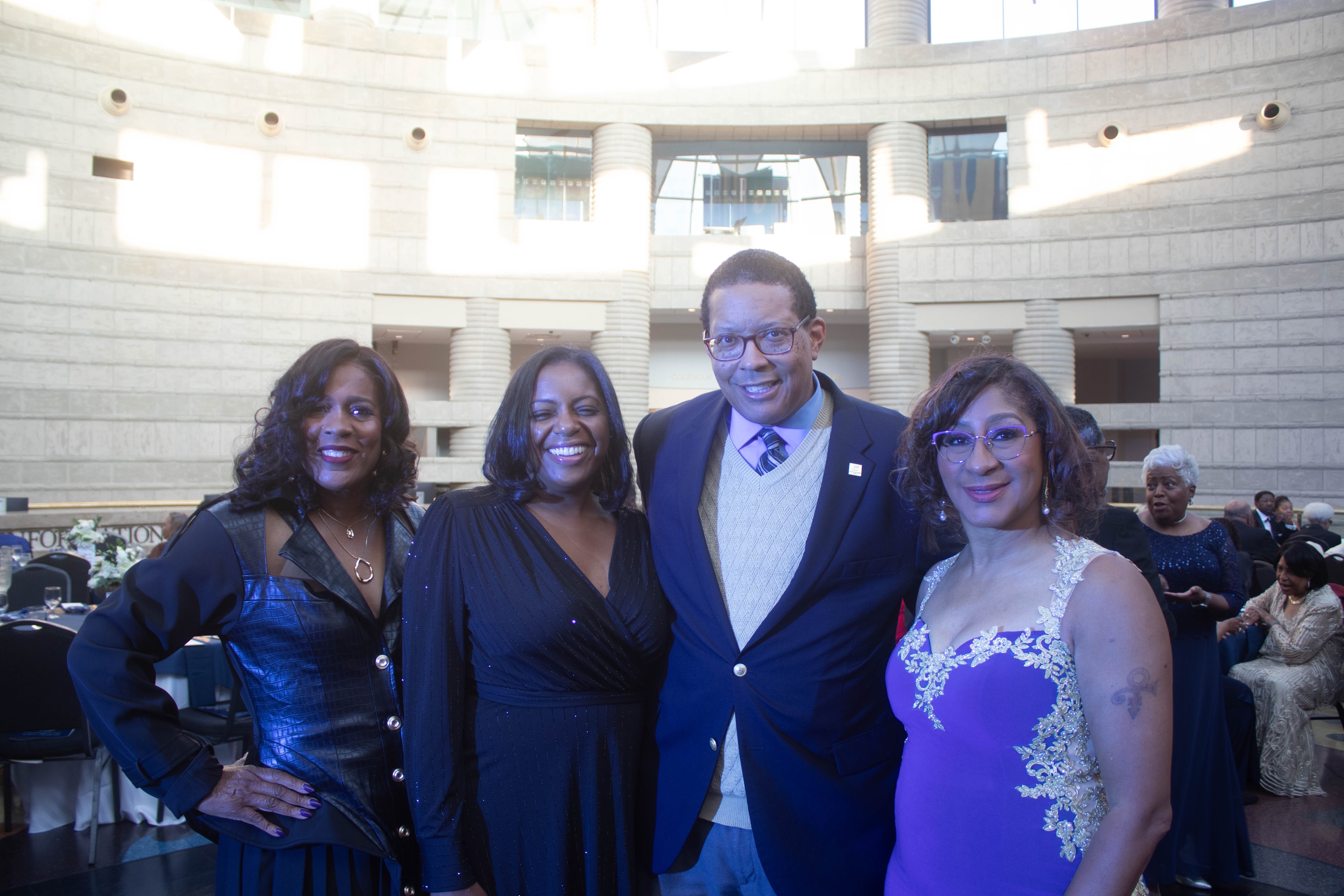 Four people posing formal event modern building