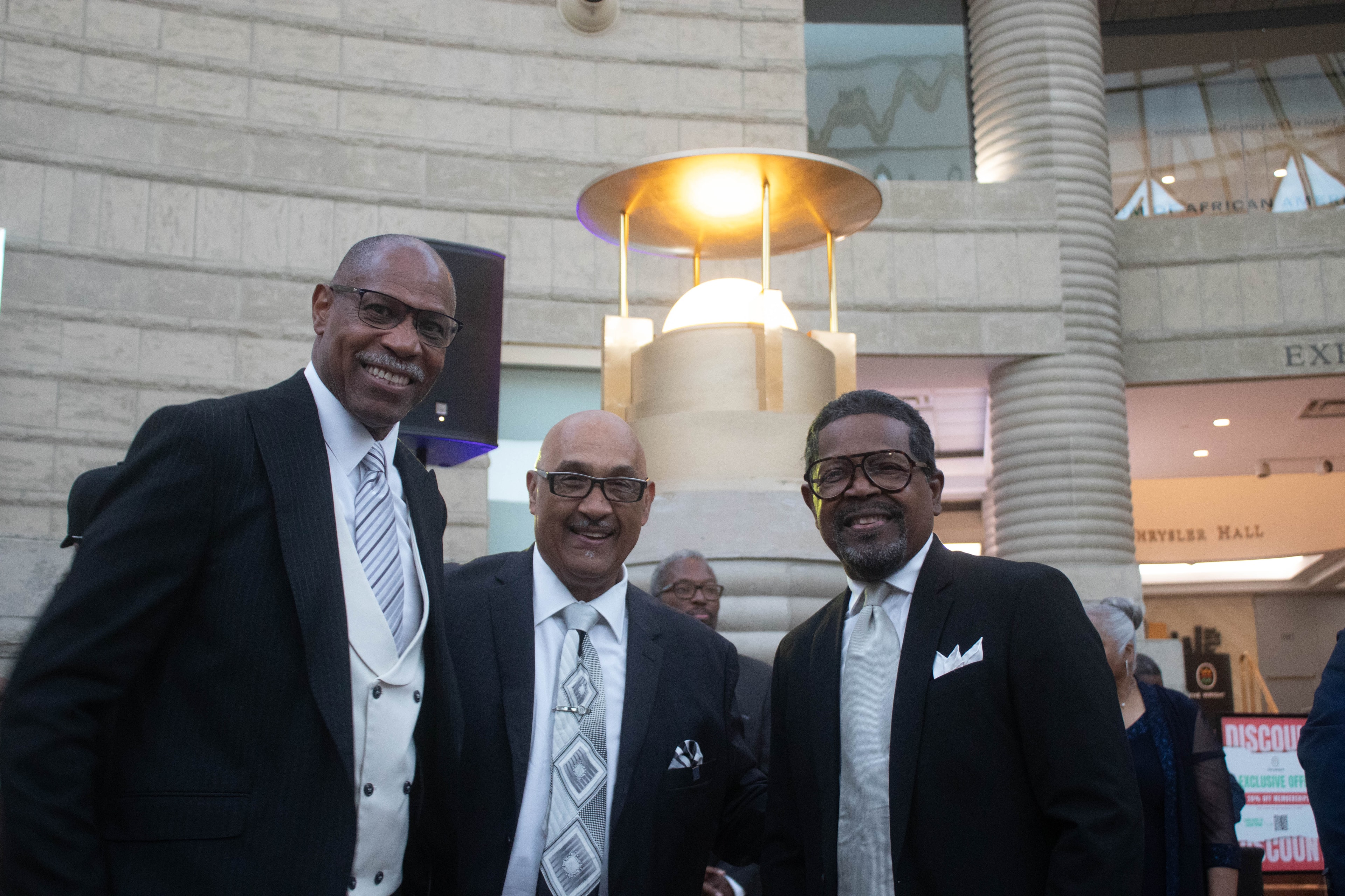 Three men in suits at formal event