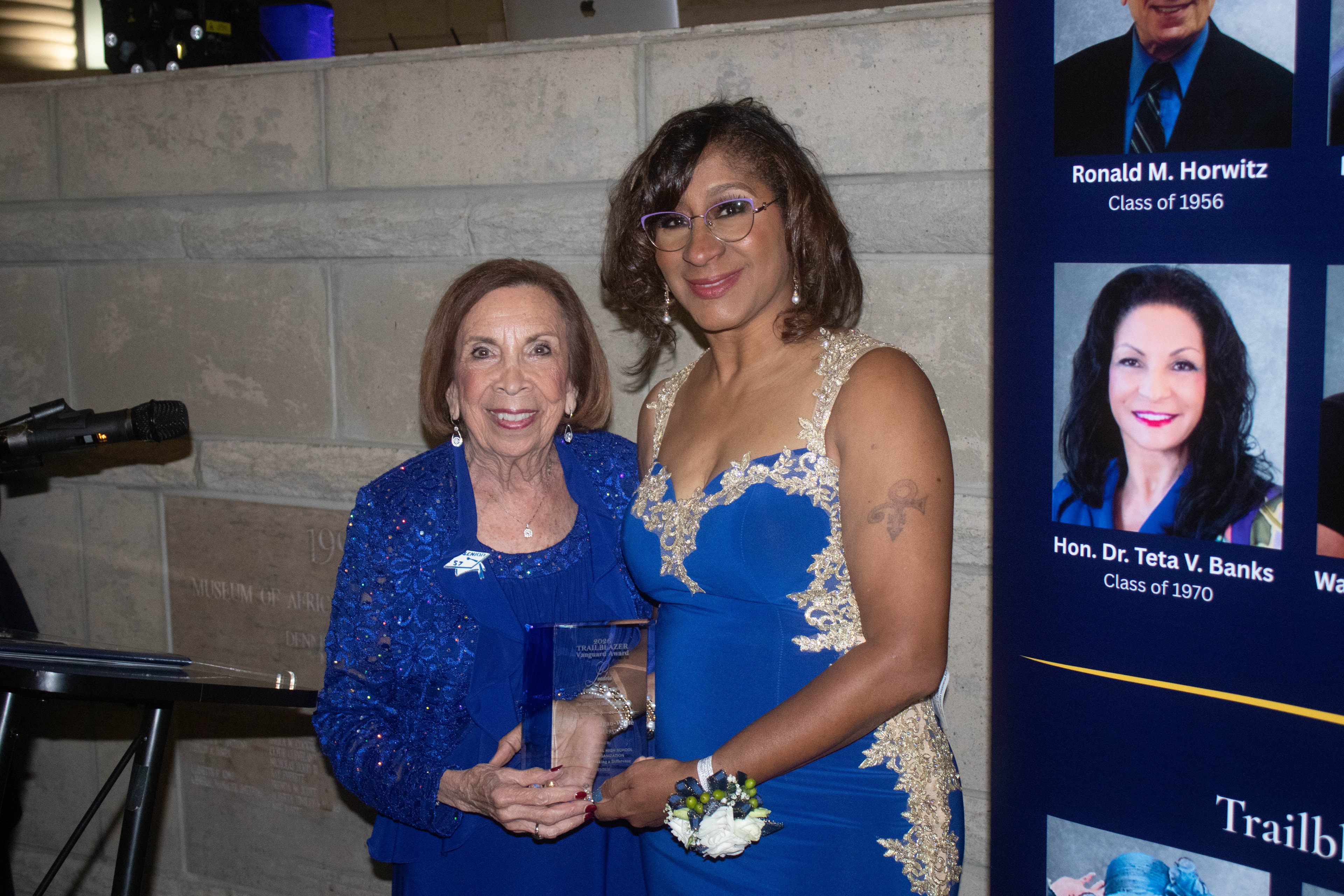 Two women holding award at formal event