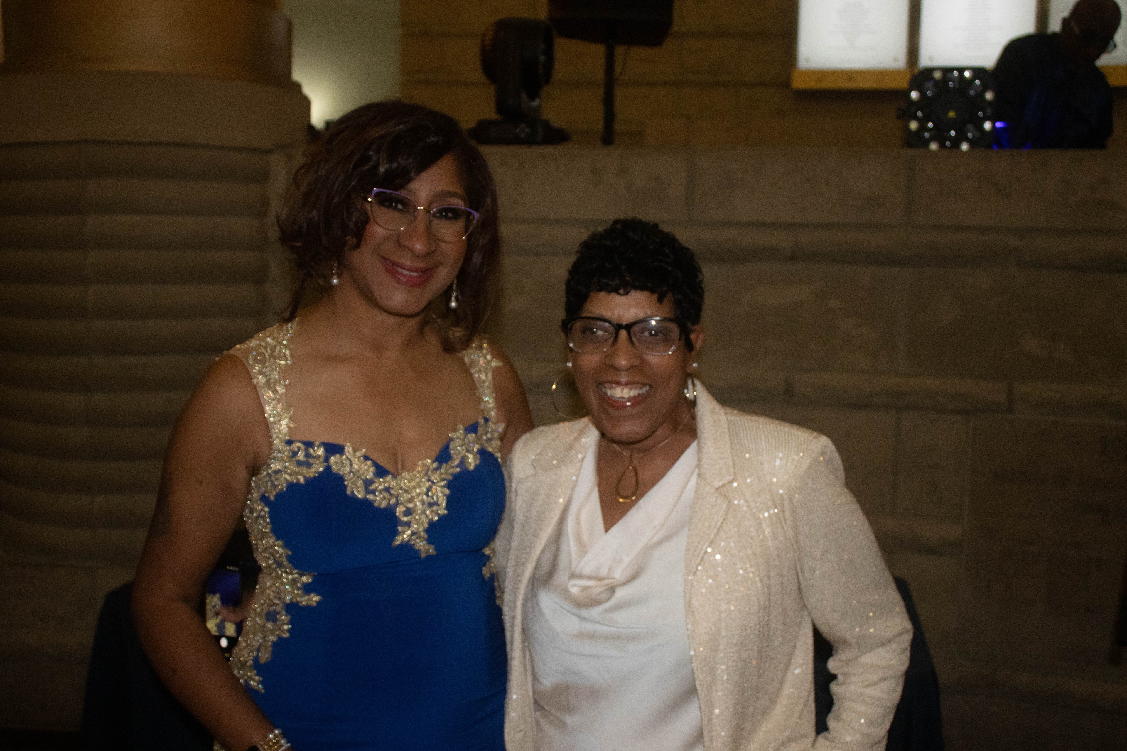 Two women in formal sequined attire smiling